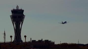 Passenger airplane ascending during golden hour near airport control tower, silhouetted against dramatic sky with antennas and airport infrastructure visible video