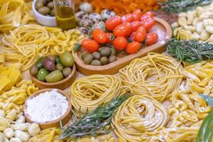 A table full of food including pasta, olives, tomatoes, and quail eggs. The table is set for a meal and the food looks delicious photo