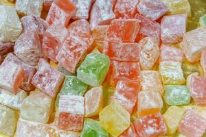 A pile of colorful jelly candies with different flavors. The candies are of different shapes and sizes, and they are all piled together on a surface. photo