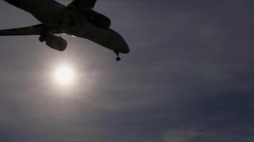 Airplane silhouette descending against radiant sun during landing, creating dramatic visual sequence with luminous backlight and serene atmospheric conditions video