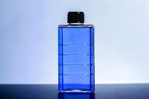 A blue bottle with a black cap sitting on a table photo