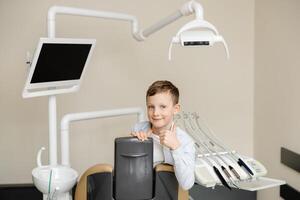 Happy boy looking at camera smiling while sitting in dentistry after teeth examination. photo