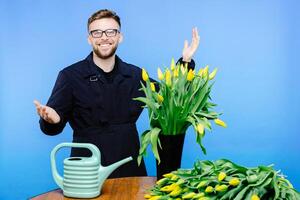 Man flower shop manager standing in apron in floral shop. Man working a with tulips in flower shop. photo