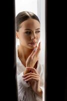Bride hiding behind curtains looking down with closed eyes and hands near her face. photo