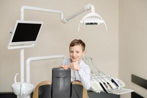 Boy looking at camera smiling while sitting in dentistry after teeth examination. photo