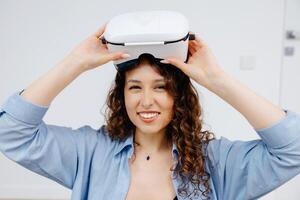 Young woman in VR glasses using modern technology creating room design, moving hands in air, sitting in new apartment during renovation. Virtual reality and repair concept photo