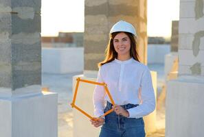 Female architect holding folding ruler on construction site at sunset. photo