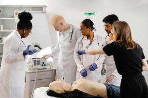 Doctors practicing cardiopulmonary resuscitation and intravenous injection on manikin. photo