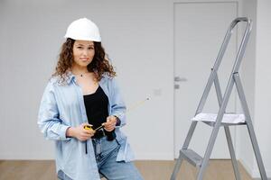 Construction and building concept. Woman in protective helmet with ruler in hand is looking to camera. photo