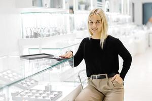 Saleswoman calculating price using calculator in jewelry shop photo