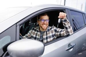 Excited man showing a car key, sitting inside new vehicle. photo