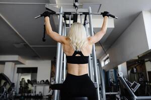 Athletic woman exercising back muscles using lat machine in gym photo