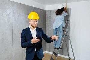 Young businessman holds a phone in his hands and checks the work of a designer in creating an interior in a room. The concept of repair on a modern design. photo