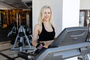 Determined sportswoman running on treadmill in modern gym photo