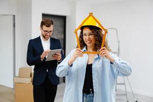 Young businessman is holding a tablet and looking at the modeling of an apartment, while a designer is standing with a ruler in her hands and looking at the camera. photo