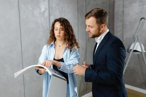 A young designer discusses the plans and design of the room with the customer. The concept of repair on a modern design. photo