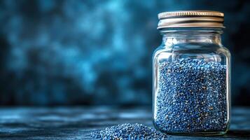 Jar filled with blue beads on a wooden table creating a decorative display in natural light photo