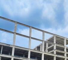 Unfinished Concrete Building Structure. A low-angle view of an unfinished concrete building structure against a cloudy sky photo