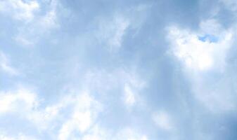 Soft Clouds in a Pale Blue Sky. A calming view of fluffy white clouds drifting across a light blue sky. Ideal for backgrounds, textures, or representing tranquility and open space. photo