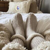 A person wearing fuzzy socks on a bed photo