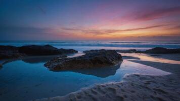 Serene beach landscape at sunset with rocks and gentle waves. photo