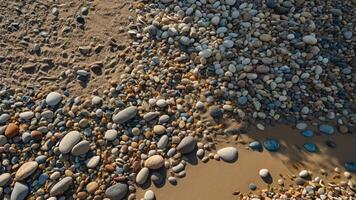 A close-up view of a sandy beach with a mix of smooth pebbles and stones. photo