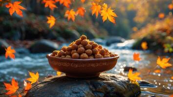 Bowl of Sweets in Autumn Landscape by Stream with Maple Leaves photo