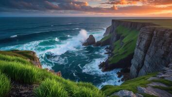 Waves Crashing Against Cliffs with Green Grass and Colorful Sky photo