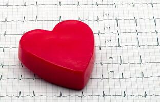 Heart-shaped object on EKG graph paper, representing health and medical concepts. photo