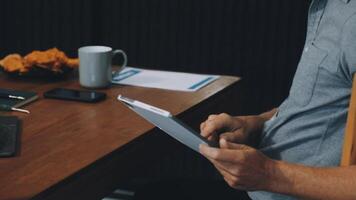 Man using tablet at desk with coffee and laptop video