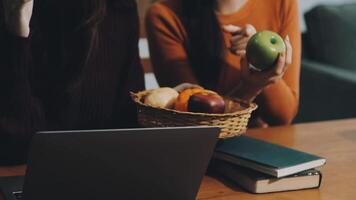 Two women sitting at a table with a laptop and a basket of apples video