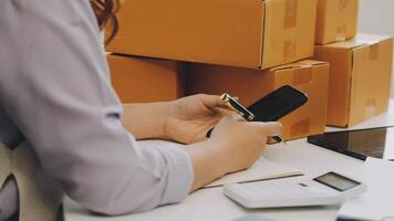 A woman is using her cell phone while sitting in front of boxes video