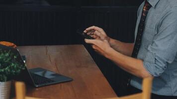 A man in a tie is using his phone while sitting at a table video