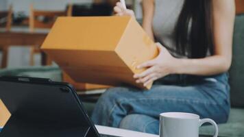 A woman is holding a box and laptop while sitting on a couch video