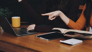 Two women sitting at a table with a laptop and book video