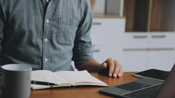 Man working at desk with laptop and notebook video