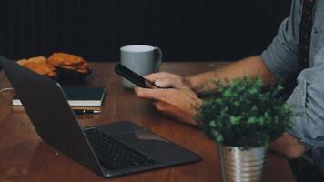 Man using laptop and mobile phone at table video