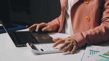 A person using a calculator and laptop on a desk video