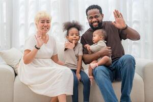 Family enjoys quality time together at home during a sunny afternoon while warmly waving to the camera photo