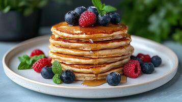 A stack of pancakes with berries and mint leaves photo