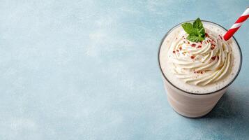 A milkshake with whipped cream and a striped straw photo