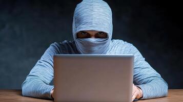 A man in a hoodie is using a laptop photo