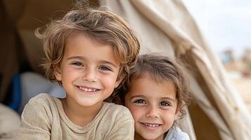 Two children are smiling in front of a tent photo