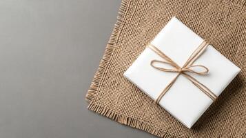 A white gift wrapped in burlock with a bow photo