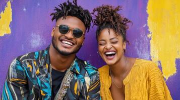 A man and woman smiling in front of a purple wall photo