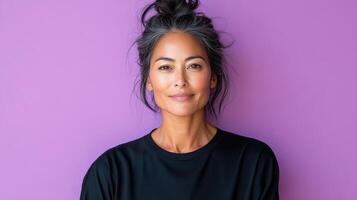 A woman with a messy bun and black top is looking at the camera photo