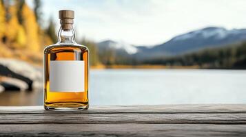 A bottle of whiskey on a wooden table in front of a lake photo