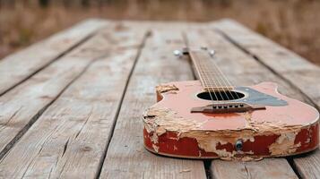 An old guitar sits on a wooden table photo