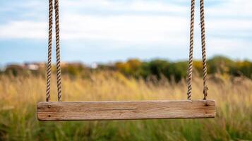 wooden swing set sways gently in breeze, surrounded by tall grass photo
