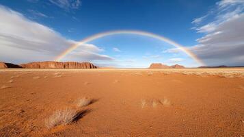 rainbow stretching across desert landscape under blue sky photo